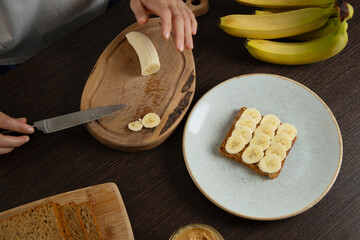 Peanut butter sandwich with banana - woman preparing breakfast.