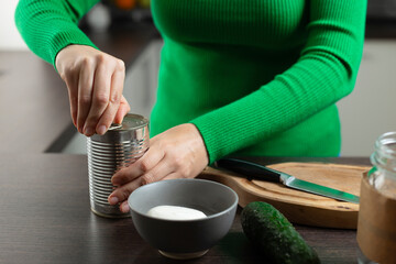 Woman opens can of chickpeas to make salad.