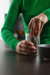 Woman opens can of chickpeas to make salad.