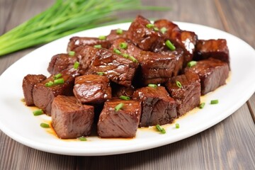bbq steak tips with garlic sprig on a white plate