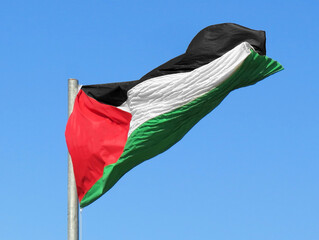 large Palestinian flag waving in the blue sky