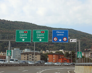 road signs for the cities of CHIASSO and Lugano near the border between Switzerland and Italy