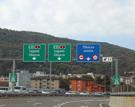 road signs for the cities of CHIASSO and Lugano near the border between Switzerland and Italy