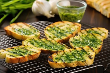 grilled bread on a cooling rack, dollop of garlic herb butter on side