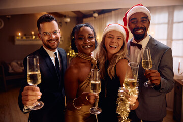Multiracial group of cheerful friends toasting on New Year's eve and looking at camera.