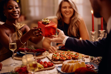Close up of black woman receives Christmas present during dinner party.