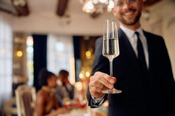 Close up of man toasting with glass of champagne during New Year party. - obrazy, fototapety, plakaty