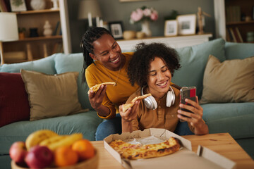 Teenage boy making selfie while having pizza with his mother at home