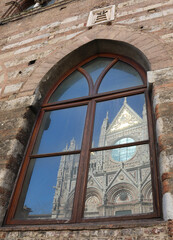 Naklejka premium reflection on window of the facade of Siena Cathedral in Italy