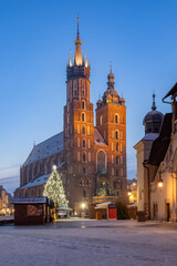 St Mary's church and Cloth Hall on snow covered Main Square in winter Krakow, illuminated in the...