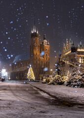 Krakow, Poland, snowy Main Market square, St Mary's church and Cloth Hall in the winter season, during Christmas fairs decorated with Christmas tree