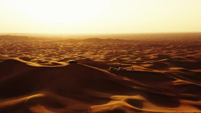 Aerial view of 4x4 off road land vehicle taking tourists on desert dune bashing safari in Dubai, UAE