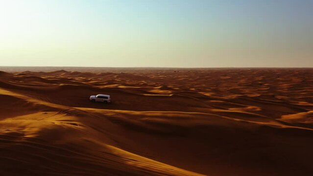 Aerial view of 4x4 off road land vehicle taking tourists on desert dune bashing safari in Dubai, UAE