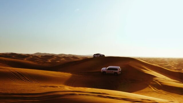 Aerial view of 4x4 off road land vehicle taking tourists on desert dune bashing safari in Dubai, UAE
