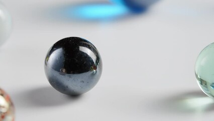 Attention grabbing transition of marbles passing on rotating white background. Closeup, macro