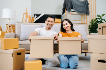 Fototapeta na wymiar Young couple with big boxes moving into a new house, new apartment for couple, young man and woman helping to lift boxes on sofa for the new home, Moving house..