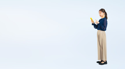 スマホを使う女性の全身写真（切り抜き背景透過PNGも販売しております。作成者リンクから「PNG」で検索してください）