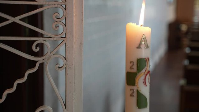 Paschal candle with symbols and burning flame inside church - closeup