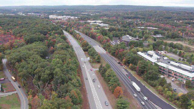 Drone footage over Donald Lynch Boulevard in Marlboro, Massachusetts. Traffic, fall foliage and mixture of commercial and residential spaces on either side of the highway.