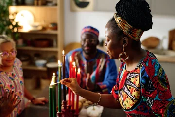 Foto op Aluminium Side view of young African American woman in ethnic apparel burning candles symbolizing seven main principles of national culture © AnnaStills
