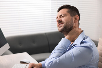 Man suffering from neck pain in office