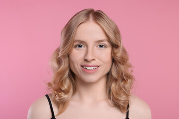 Portrait of beautiful woman with blonde hair on pink background