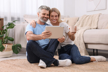 Happy affectionate couple with tablet at home. Romantic date
