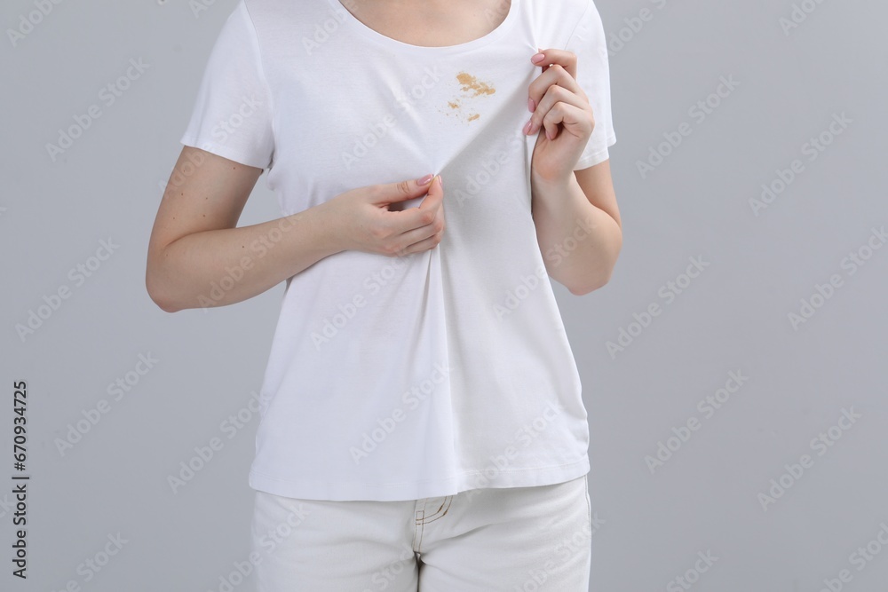 Canvas Prints Woman showing stain on her t-shirt against light grey background, closeup