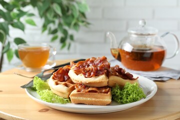 Tasty Belgian waffles served with bacon, lettuce and tea on wooden table