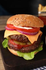 Tasty cheeseburger with patties and tomato on table, closeup