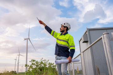 Engineer wearing uniform inspection and survey work in wind turbine farms rotation to generate electricity energy. Maintenance engineer working in wind turbine farm at sunset.