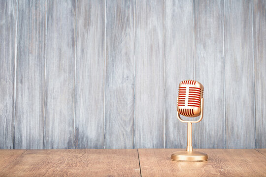 Vintage classic golden microphone for press conference or interview on the desk front old wooden wall background. Retro style filtered photo