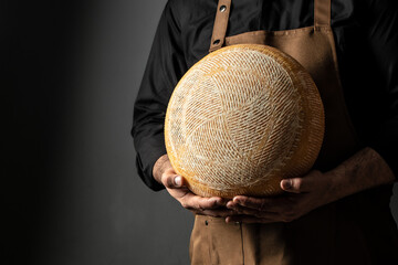 Cheesemaker is controlling the seasoning lots of wheels of cheese. Female hands holding various...