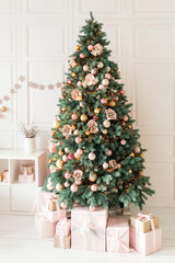 Christmas home interior. White room with a large decorated Christmas tree, gift boxes. Holiday decor.