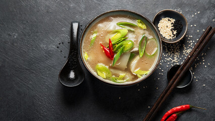 Bowl of leek soup with chili pepper on dark background. Food concept