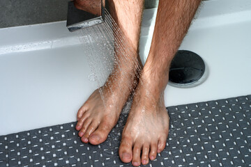 Facet myje owłosione opalone nogi w kabinie prysznicowej  - obrazy, fototapety, plakaty