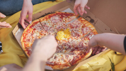 Young students' hands reach for the pizza.