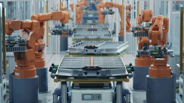 Time-lapse of Automated Production Line with Orange Robotic Arms. EV Battery Pack for Automotive Industry Assembly. Electric Car Smart Factory. Battery Manufacturing Line Equipped with Robot Arms