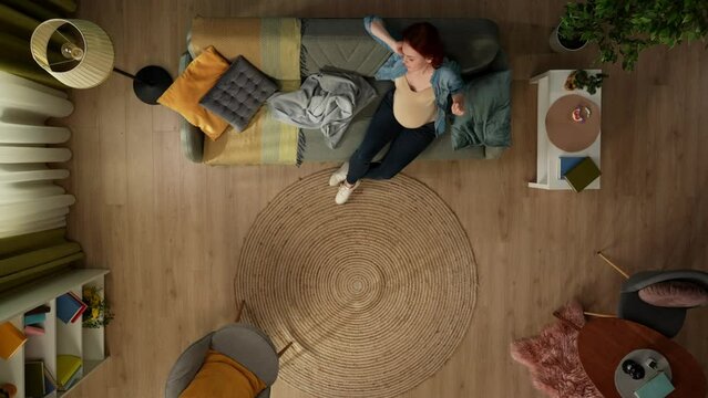 In the shot above, a pregnant woman sits on a couch in a room. She then picks up a plaid, covers herself and begins to doze off. Hugging her belly and stroking it a bit she smiles.