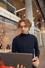 Focused entrepreneur working on laptop standing in modern coworking during working day