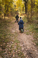 Family walking with kids in the autumn forest with yellow bright leaves