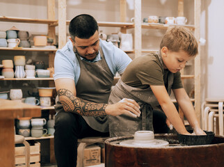 Confident handsome man and little boy making ceramic pot on the pottery class