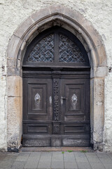 Fototapeta na wymiar Old decorative wooden entrance door to the church. Large wooden arched gates with carved details, decorative metal elements and handles