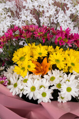 Beautifully designed bouquet of white, yellow and pink chrysanthemums on a light background. Top view, close-up.