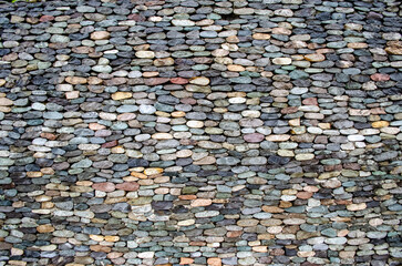 A wall of colored stones of regular shape, the focus is opposite, an interesting texture, a motley background, a natural fence made of natural materials