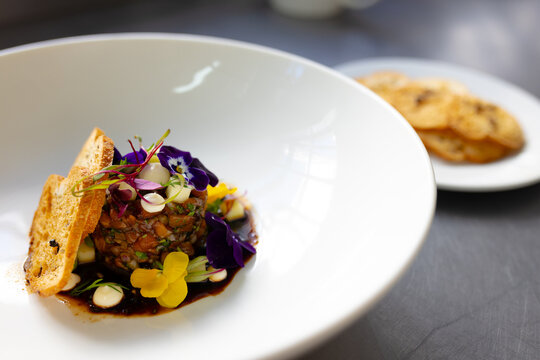 Prepared and decorated meal in white bowl in restaurant kitchen, copy space