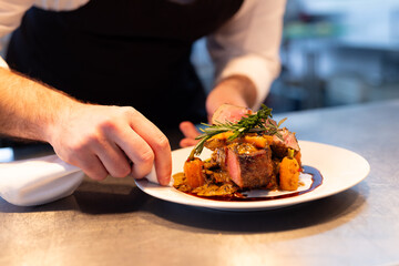 Caucasian male chef decorating meal on plate in restaurant kitchen