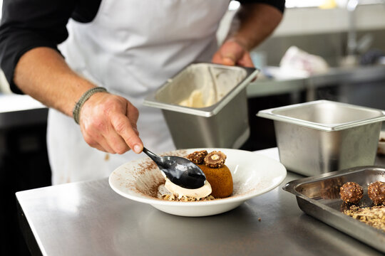 Caucasian male chef preparing meal on plate in restaurant kitchen