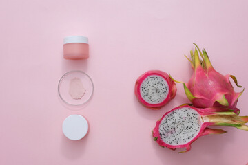 Fototapeta na wymiar Top view of unlabeled cosmetic jar with fresh dragon fruit and some props on pink background. Health and beauty themes. Image suitable for magazines.