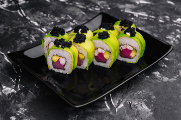Sushi roll covered with avocado with tuna and black caviar